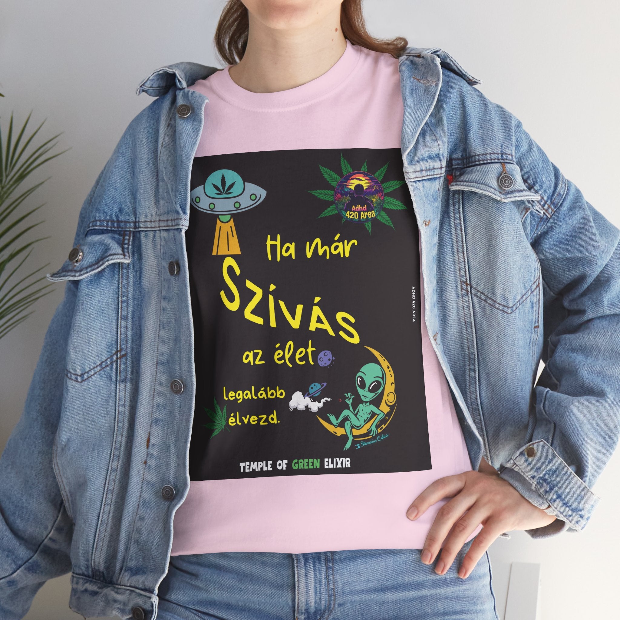 Model trägt Jeans Jacke und hellrosa T-Shirt mit buntem Grafikdesign: Ein UFO, ein Hanfblatt, ein Außerirdischer auf einer Mondsichel, der raucht, und der ungarische Schriftzug „Ha már szívás az élet, legalább élvezd. Temple of Green Elixir“ und „Adhd 420 Area“ Logo ist ebenfalls enthalten.