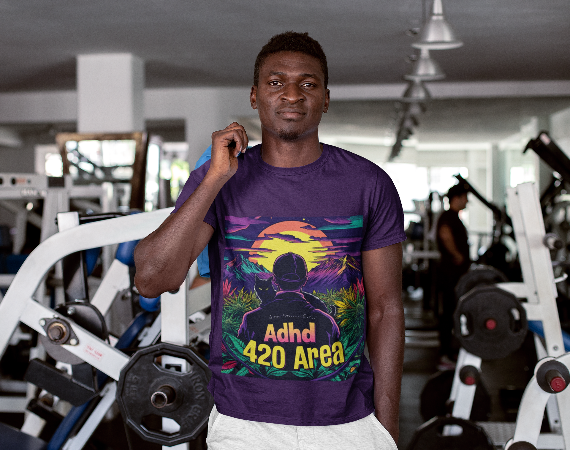 Ein Mann im Fitnessstudio trägt ein lila ADHD 420 Area T-Shirt. Das Motiv zeigt eine friedliche Landschaft im warmen Licht des Sonnenuntergangs, in der die Hauptfigur – in Begleitung ihrer treuen schwarzen Katze – durch ein Cannabisfeld streift und die Ruhe der Natur genießt.
