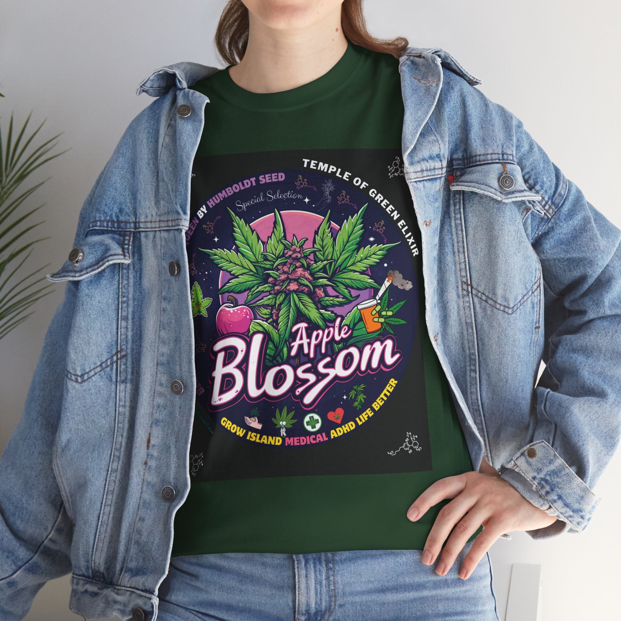 Model steht im Jeans Jacke und Apple Blossom grünes T-shirt. Die Grafik entführt dich in eine magische Nacht, in der zwischen lilafarbenen Blüten eine Cannabis-Pflanze mit Apfelblüten-Charakter die Szenerie dominiert. Im Hintergrund strahlt der Vollmond und taucht die Szene in zartes Rosélicht, während kleine Symbole und verspielte Illustrationen die vielseitigen medizinischen und freizeitlichen Werte der Cannabispflanze widerspiegeln.