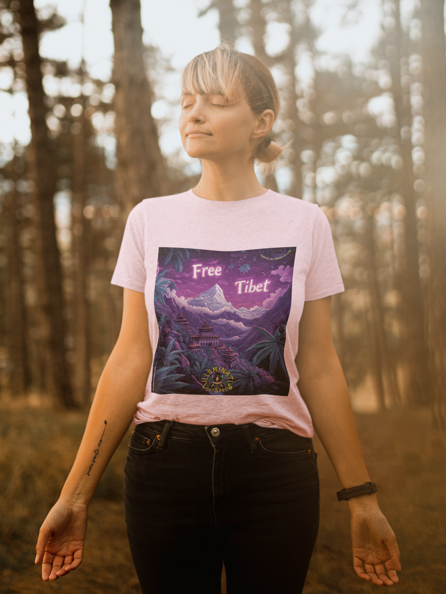 Frau steht im Wald und trägt ein hellrosa T-Shirt mit Aufdruck ‚Free Tibet‘ und Berglandschaft sowie tibetischen Gebäuden. Landschaft mit schneebedecktem Berg und traditionellen tibetischen Gebäuden, umgeben von großen grünen Cannabis-Pflanzen, vor violettem Himmel. Oben steht der Schriftzug ‚Free Tibet‘, unten das Illuminati Lost Seeds Logo.