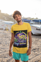 Ein Junge steht auf dem Beach in gelbem Grape Gasoline T-shirt, hinter ihm Schiffe auf dem Ufer.  Das Design des T-shirts ist einer neonbeleuchteten Nacht, in der lilafarbene Trauben und Cannabisblätter neben einer Retro-Tankstelle erstrahlen. Im Hintergrund rast ein Raumschiff über den Himmel, als würde es mit interstellarer Geschwindigkeit zum nächsten Stopp fliegen. 