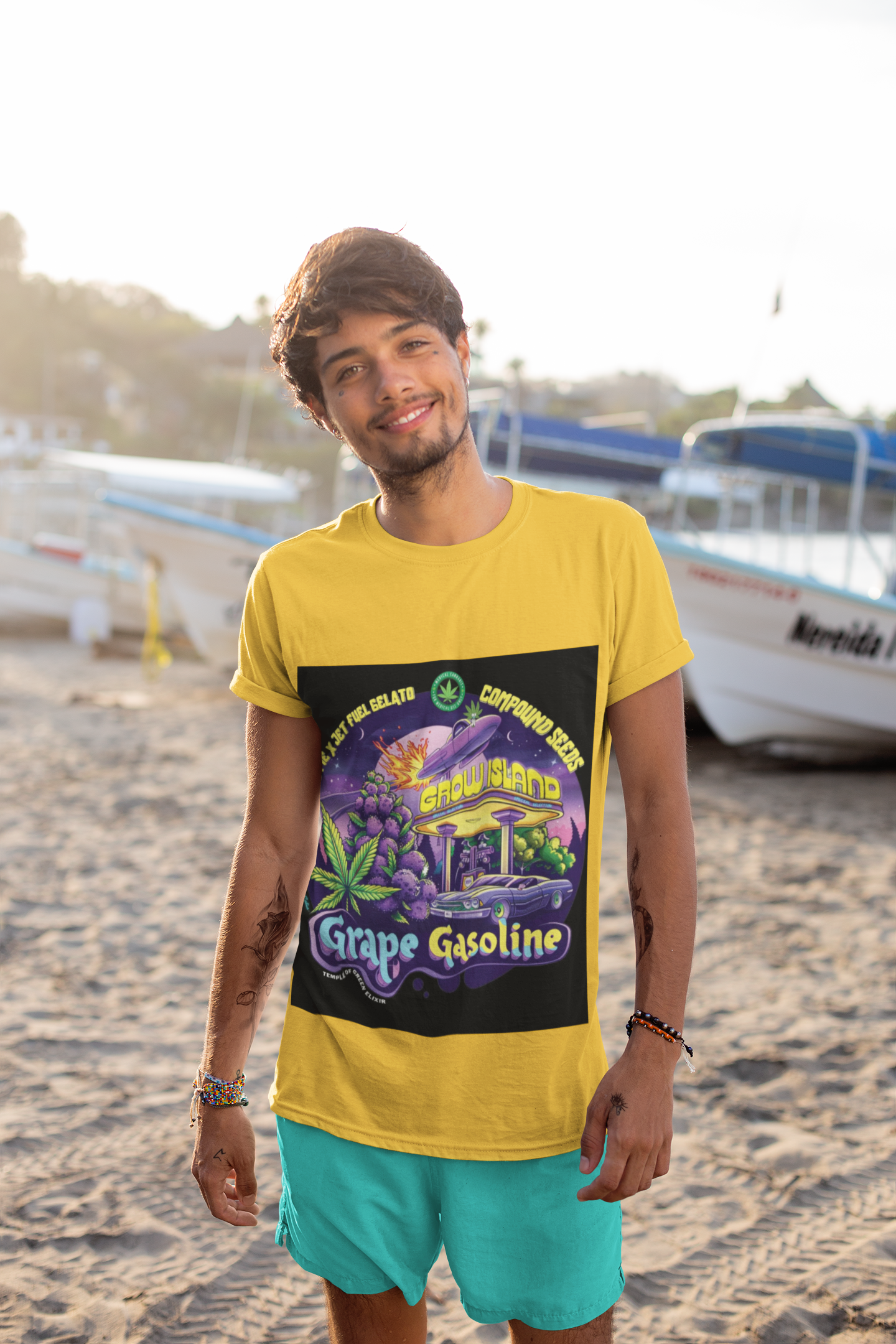 Ein Junge steht auf dem Beach in gelbem Grape Gasoline T-shirt, hinter ihm Schiffe auf dem Ufer.  Das Design des T-shirts ist einer neonbeleuchteten Nacht, in der lilafarbene Trauben und Cannabisblätter neben einer Retro-Tankstelle erstrahlen. Im Hintergrund rast ein Raumschiff über den Himmel, als würde es mit interstellarer Geschwindigkeit zum nächsten Stopp fliegen. 