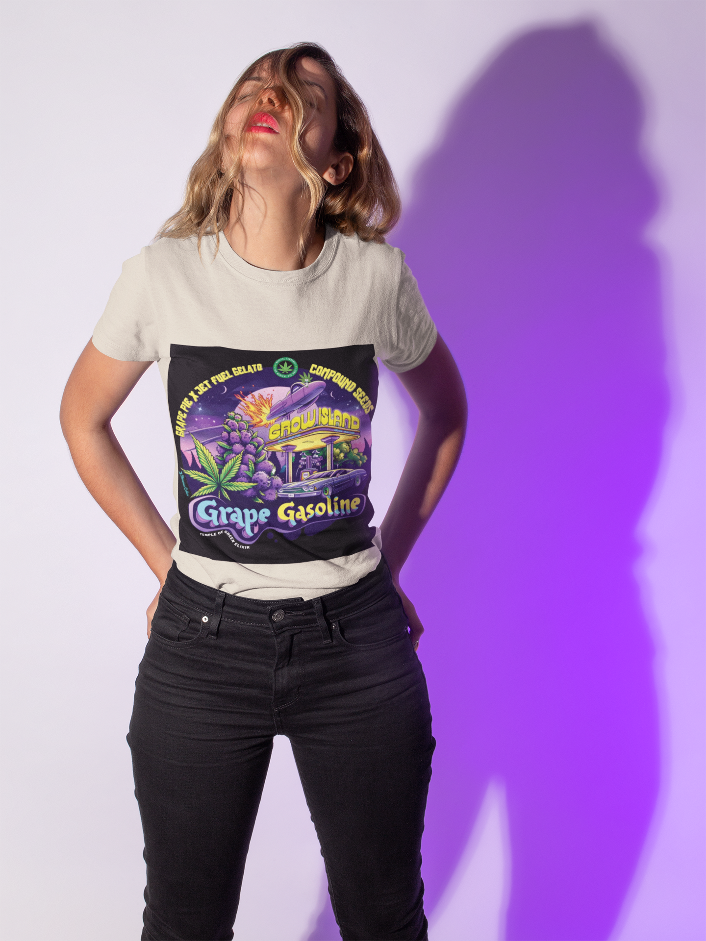Eine junge Dame steht mit in die Taschen gesteckten Händen und nach hinten geneigtem Kopf vor einem lilafarbenen Hintergrund und trägt ein Grape Gasoline sand T-Shirt. Das Design des T-Shirts ist einer neonbeleuchteten Nacht, in der lilafarbene Trauben und Cannabisblätter neben einer Retro-Tankstelle erstrahlen. Im Hintergrund rast ein Raumschiff über den Himmel, als würde es mit interstellarer Geschwindigkeit zum nächsten Stopp fliegen. 