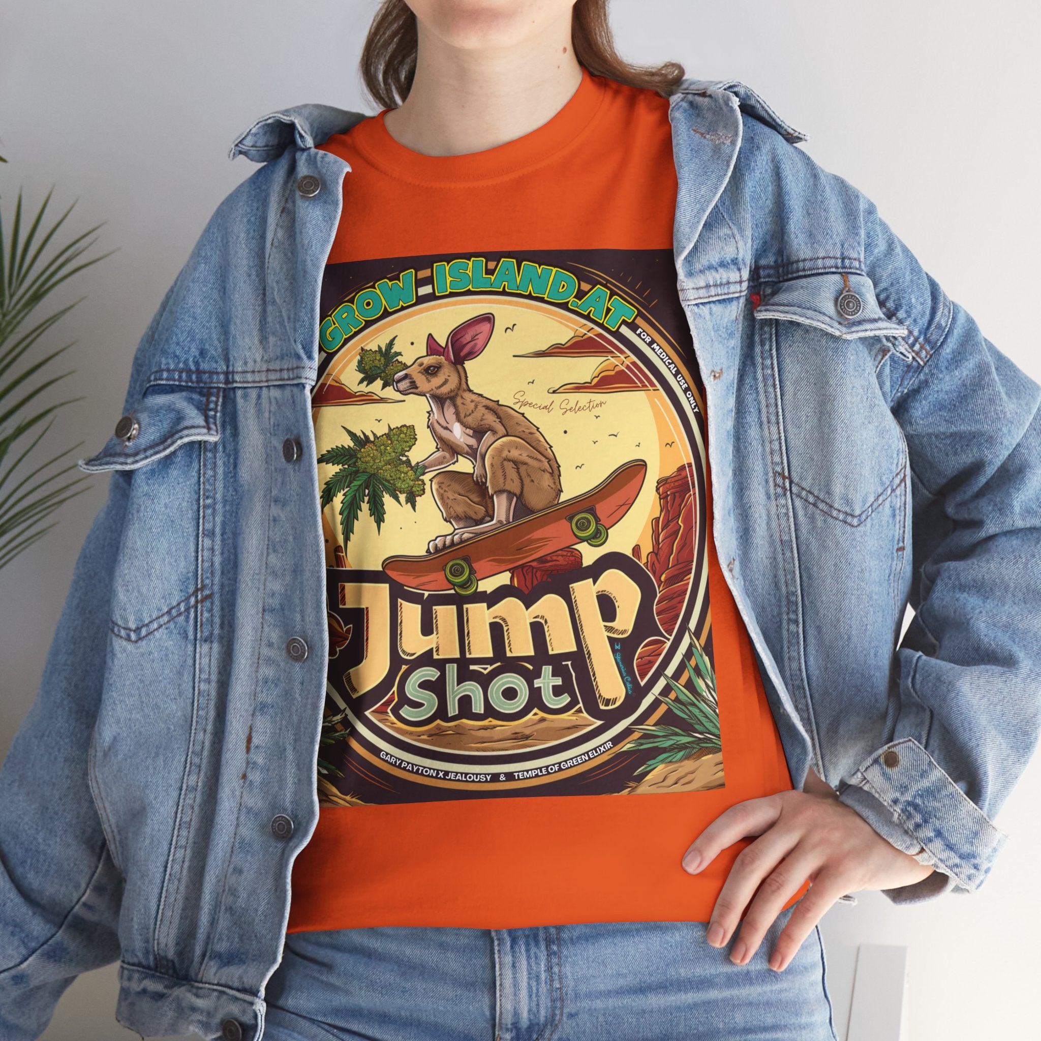 Model steht im Jeans Jacke und Jump shot oranges T-shirt.  Im Mittelpunkt der Grafik steht ein skateboardfahrendes Känguru, das stolz einen frischen, harzreichen Cannabiszweig in der Pfote hält. Die roten Felsen im Hintergrund und die warmen Töne des Wüstensonnenuntergangs rufen das Gefühl von Freiheit und den wilden Westen wach. 