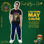 Mann im schwarzen Jurassic Haze Shirt kombiniert mit karierten Freizeitpants. Das detailreiche Artwork zeigt einen T-Rex im Sonnenuntergang – ein markanter Look für Individualisten mit Humor und Stil. Aus der Kollektion von von Temple of Green Elixir