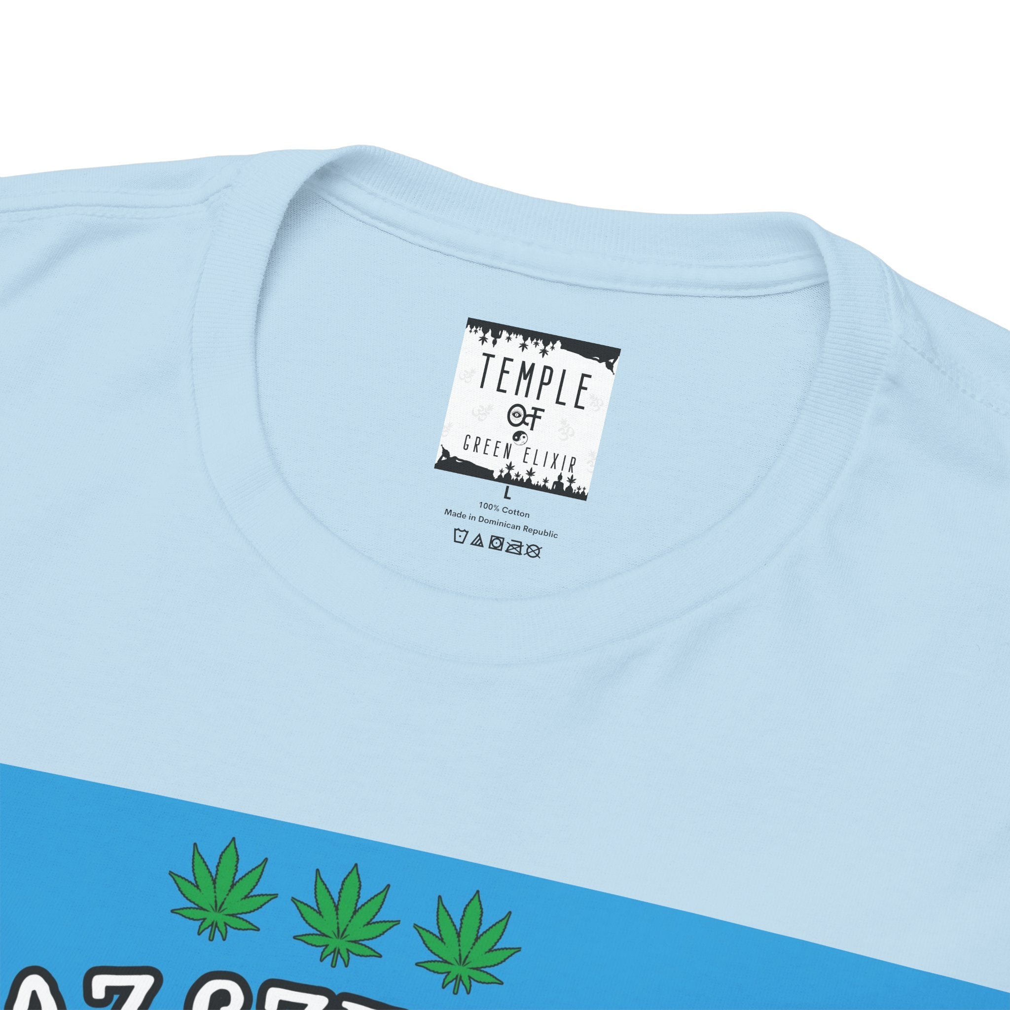 Nahaufnahme des Innenlabels eines hellblauen Wahre Liebe T-Shirts der Marke Temple of Green Elixir, das Informationen zu Material (100% Baumwolle), Herkunft (Made in Dominican Republic) und Pflegeanweisungen enthält.﻿