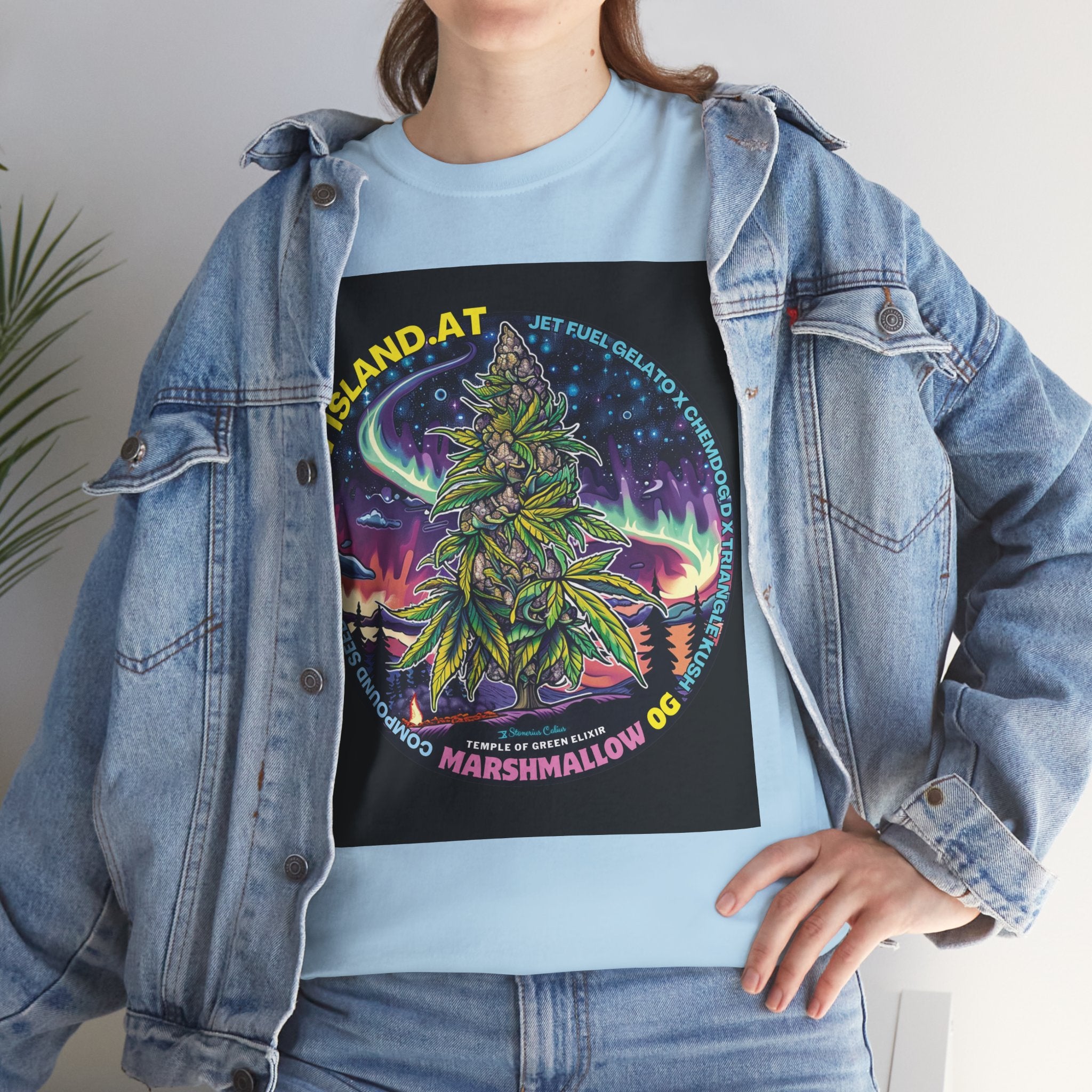 Model steht im Jeans Jacke und blaues Marshmallow OG T-shirt, zeigt das Design eine riesige Cannabis Pflanze mit kristallbedeckten Buds unter einem nächtlichen Himmel, umgeben von Nordlichtern und fernen Galaxien. 