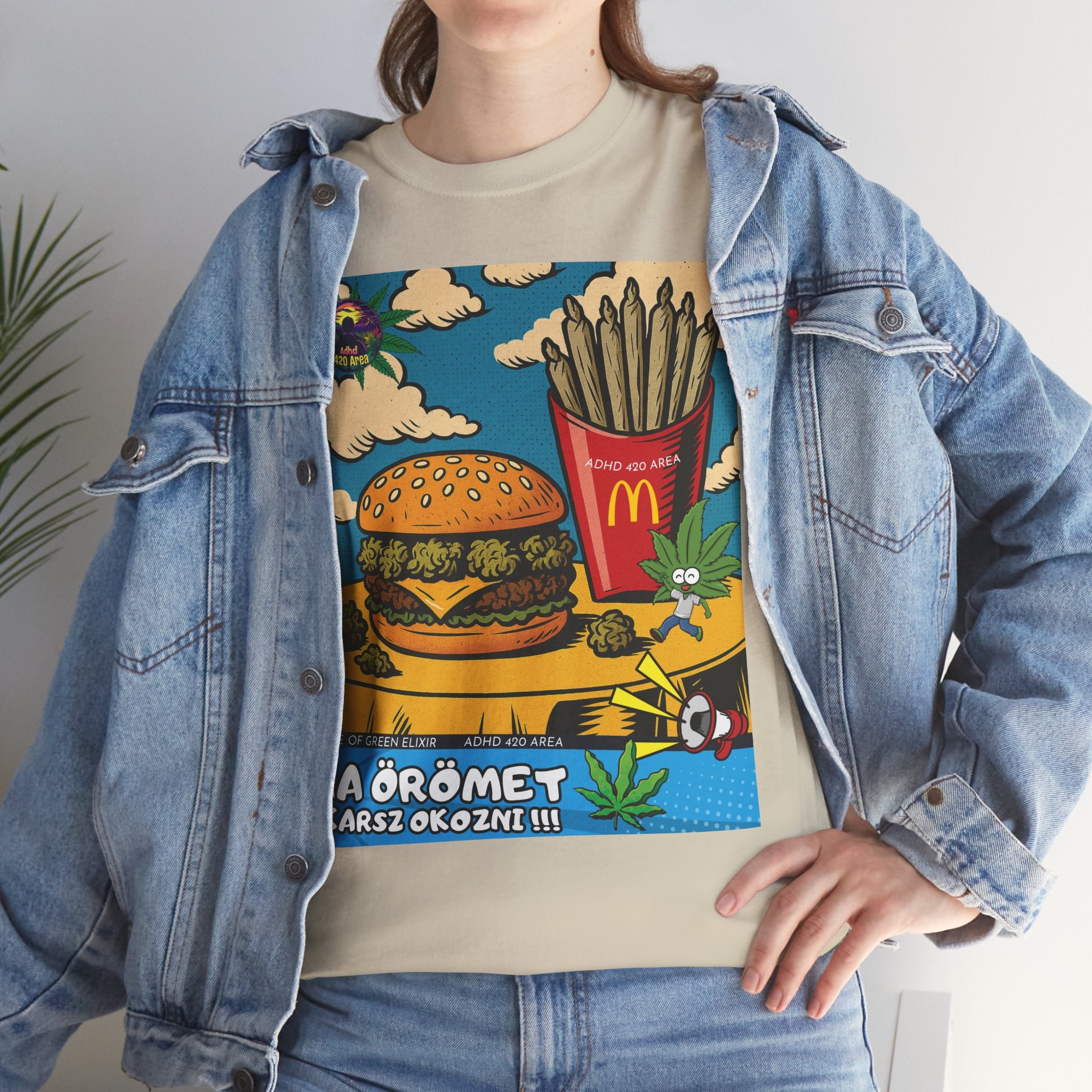 Modell in Jeans Jacke trägt ein humorvolles Hamburger T-Shirt-Design, das ein Fast-Food-Tablett im Comic-Stil zeigt. Der Burger enthält Hanfblüten, und die Pommes frites sind als Cannabis-Zigaretten dargestellt. Eine kleine Cannabisblatt-Figur läuft über den Tisch.﻿