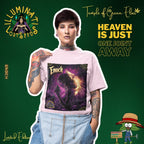 Ein Model mit kurzem Haar, Tattoos an den Armen und Piercings im Gesicht präsentiert das "Enoch" Temple of Green Elixir T-Shirt in Hellrosa. Die Person trägt eine Latzhose und blickt selbstbewusst in die Kamera. Der Kontrast zwischen dem alternativen Stil des Models und dem spirituellen, fast zarten Motiv des T-Shirts erzeugt eine einzigartige Spannung.