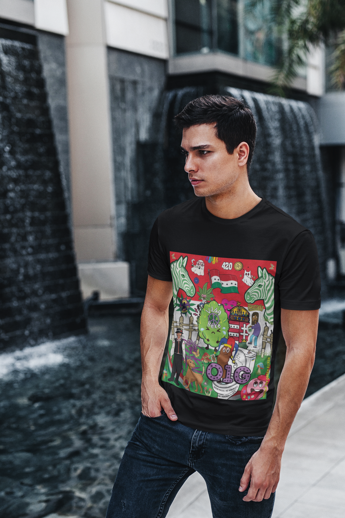 Ein junger Mann mit dunklen Haaren steht mit der Hand in der Hosentasche vor einem modernen, architektonischen Wasserfall. Er trägt ein schwarzes Weltfrieden T-Shirt von Temple of Green Elixir mit einem detailreichen, bunten Aufdruck, der eine satirische Collage aus ungarischen und Cannabis-bezogenen Cartoon-Motiven zeigt.
