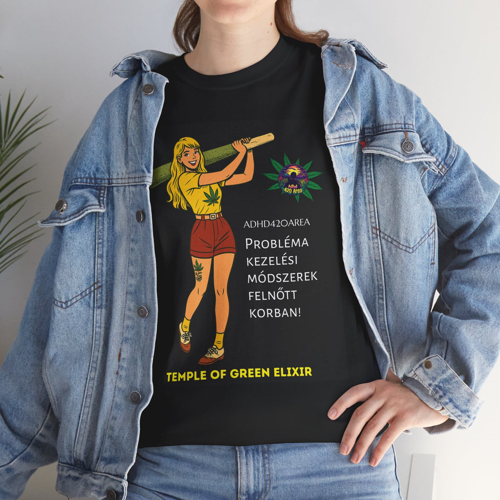 Junge Frau trägt ein schwarzes T-Shirt mit einer Grafik einer gezeichneten Figur, die eine große grüne Zigarette hält. Daneben sind Hanfblätter und der Text auf Deutsch: „ADHD42QAREA Problembehandlungsmethoden im Erwachsenenalter! Temple of Green Elixir“. Sie steht vor weißem Hintergrund und trägt eine blaue Jeansjacke.