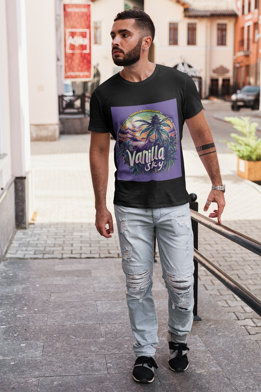 Ein junger Mann spaziert auf der Straße und trägt ein schwarzes Vanilla Sky T-Shirt mit Kreatives Cannabis-Design mit tropischem Inselmotiv und lila Himmel, großer „Vanilla Sky“-Schrift, Cannabispflanzen im Vordergrund, Sonnenuntergang und Palmen – medizinische Sorte GMO x Garlic Breath x Cali Grow Island von Grow Island.