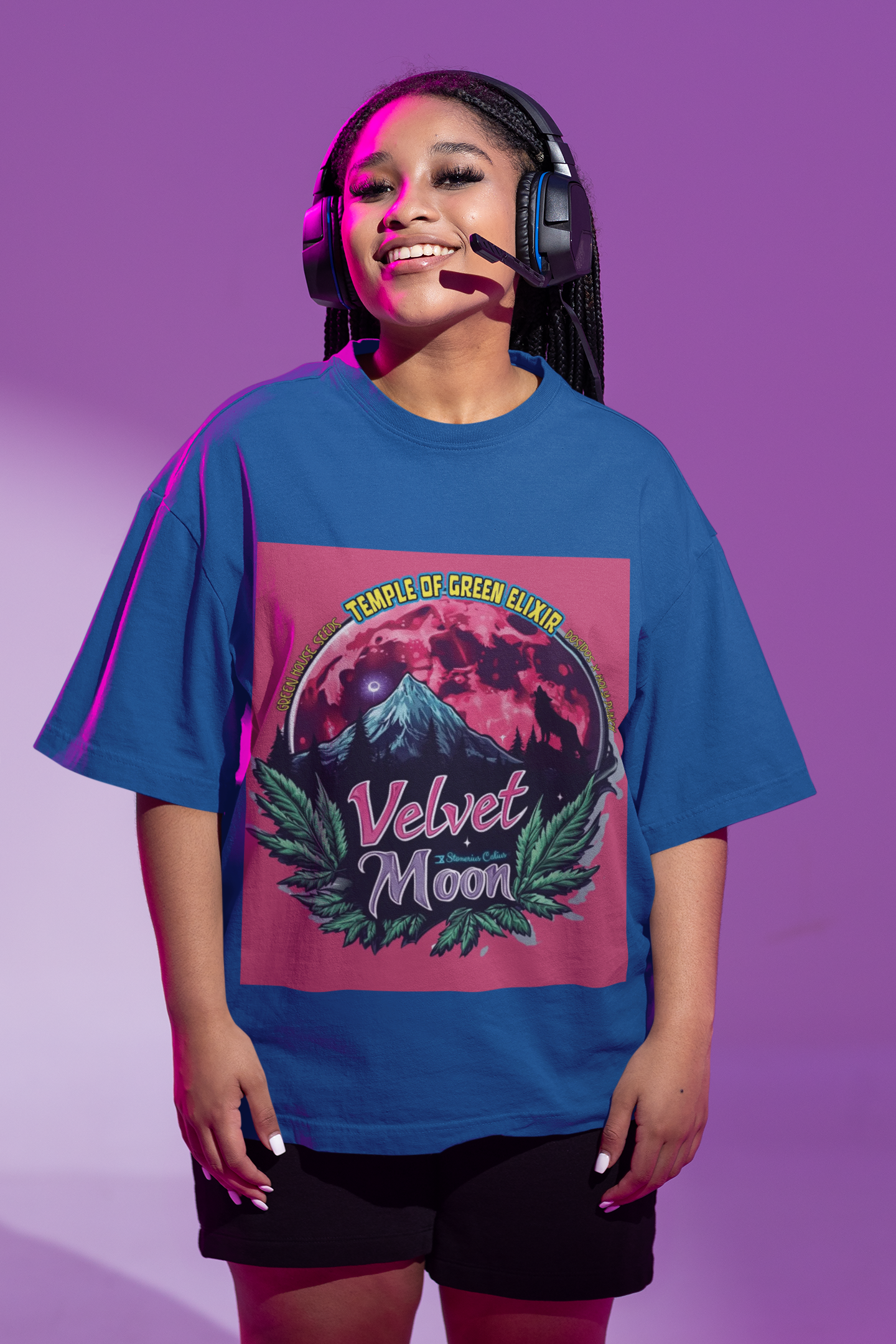 Eine junge Dame steht in Shorts und blauem Velvet Moon T-Shirt mit Kopfhörern auf dem Kopf vor einem lila Hintergrund. Die Grafik erzählt von einer besonderen Nacht, in der das samtige Licht des blutroten Mondes die Berggipfel umhüllt und ein einsamer Wolf in den Schatten der dunklen Wälder hineinheult. Die Luft ist erfüllt vom Duft der frischen Bergluft, die die Freiheit der Wildnis und den Zauber des Unbekannten mit sich bringt. Cannabisblätter rahmen die Szene ein.