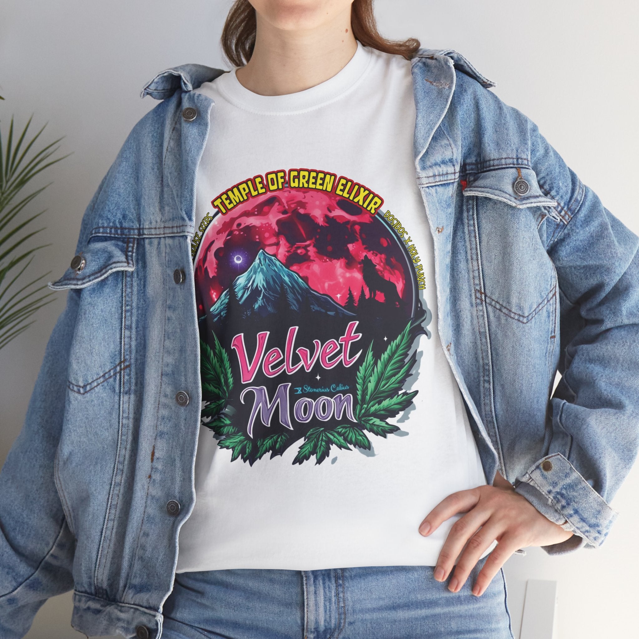 Model steht im Jeans Jacke und weisses Velvet Moon T-shirt.  Die Grafik erzählt von einer besonderen Nacht, in der das samtige Licht des blutroten Mondes die Berggipfel umhüllt und ein einsamer Wolf in den Schatten der dunklen Wälder hineinheult. Die Luft ist erfüllt vom Duft der frischen Bergluft, die die Freiheit der Wildnis und den Zauber des Unbekannten mit sich bringt. Cannabisblätter rahmen die Szene ein, als würde die Natur selbst diesen geheimen Moment beschützen. 