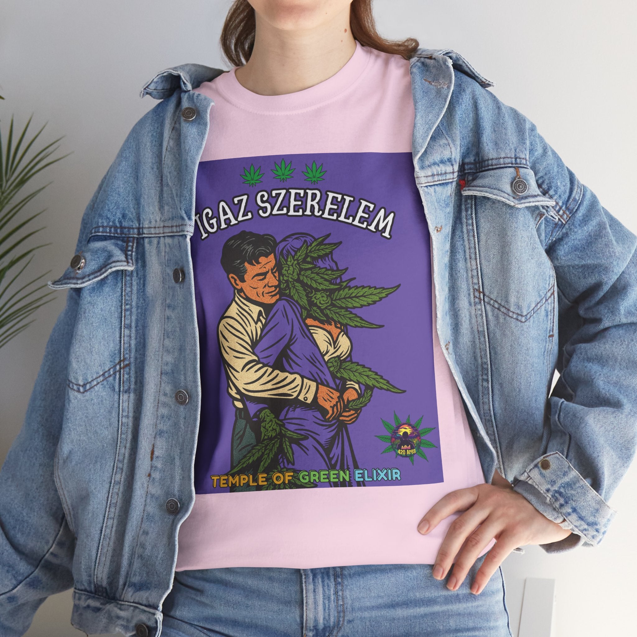 Ein Model steht in Jeans Jacke und hellrosa wahre Liebe  T-Shirt mit einer humorvollen Darstellung von "Wahrer Liebe": Ein Mann im 50er-Jahre-Stil hält eine Frau mit einer großen Hanfblüte als Kopf im Arm.﻿