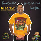 Mann steht mit verschränkten Händen in der Tasche, trägt ein gelbes  Wasen Brezer T-Shirt und lächelt. Im Hintergrund verschiedene Schriftzüge wie ‚Temple of Green Elixir‘, ‚Stay High, Stay Focused‘ und animierte Logos. Auf dem T-shirt Frau im Dirndl hält ein Bierglas mit ‚Wasen Brezer‘-Aufschrift und eine Brezel, umgeben von grünen Pflanzen vor Sonnenuntergang. Oben links das Logo ‚Illuminati Lost Seeds‘, unten der große Schriftzug ‚Wasen Brezer‘ und die Webseite.