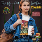 Junge Frau trägt Jeansjacke und weißes Wasen Brezer T-Shirt, hält einen Kaffeebecher in der Hand und hat eine braune Tasche auf dem Rücken. Auf dem T-Shirt Frau im Dirndl hält ein Bierglas mit ‚Wasen Brezer‘-Aufschrift und eine Brezel, umgeben von grünen Pflanzen vor Sonnenuntergang. Oben links das Logo ‚Illuminati Lost Seeds‘, unten der große Schriftzug ‚Wasen Brezer‘ und die Webseite.