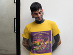 Tatowierte Mann steht vor der Wand im Wy-Kiki gelbes T-shirt, Am Horizont versinkt die Sonne langsam im Meer, die Schatten der Palmen werden lang, und in der Luft liegt der Duft von Salz, Früchten und frisch getrockneten Cannabis Blüten. Im Mittelpunkt steht eine entspannte, stilvolle Frau, die an einem exotischen Drink nippt – darin schwimmen keine Zitronen oder Limetten, sondern kleine, perfekte Cannabis Buds, als würde sie die Essenz des Sommers trinken. 